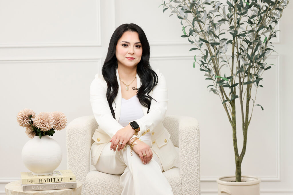 corporate woman in white pants suit sitting on a white bouclee chair in San Antonio photo studio