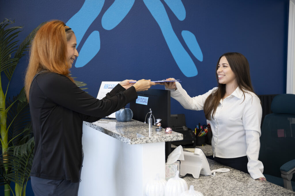desk attendant taking client intake form at physical therapy office