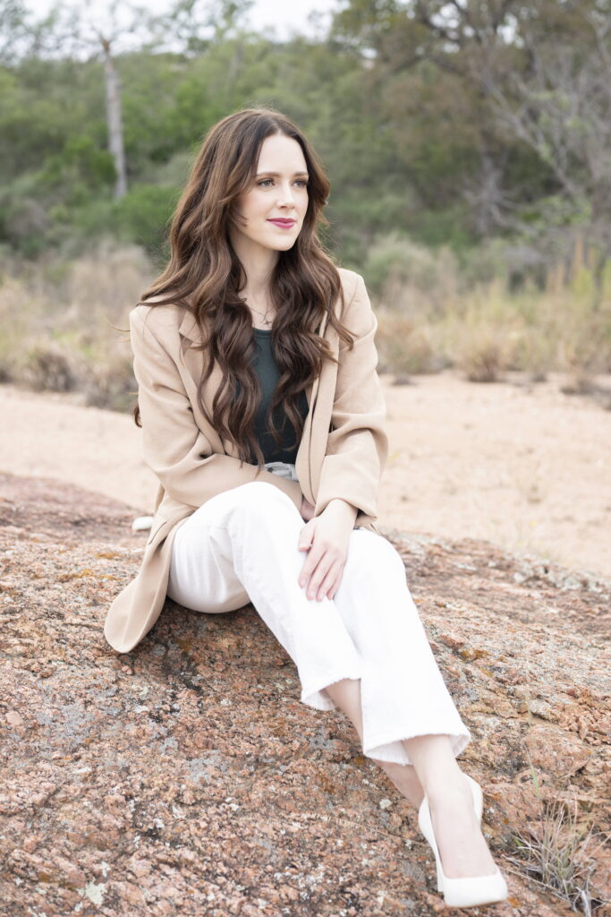 woman in a blazer and white pants sitting on enchanted rock